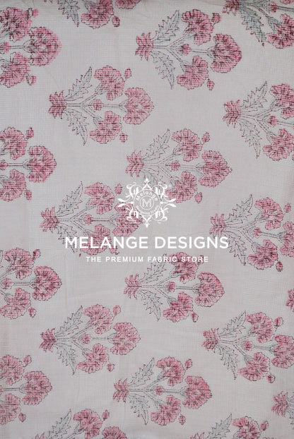 A close-up of a Printed Cotton Cotta Fabric  with a repeating floral block print pattern in pink and gray on a light beige .