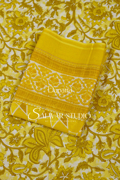 A folded yellow dupatta with a white floral pattern and gold borders.