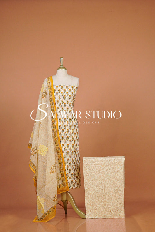 A cream-colored ethnic suit set featuring a printed kurta, matching dupatta, and a folded fabric box. 