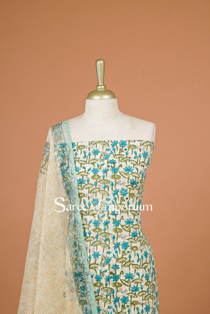 A traditional Indian salwar suit set  The set features a white base fabric with blue floral embroidery, a matching blue and green printed dupatta, and a beige embroidered border.