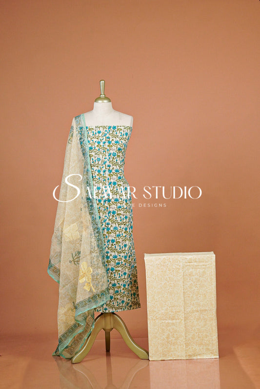 A sleeveless embellished dress displayed on a mannequin against a peach studio background, with a matching sheer dupatta draped over the shoulders and a folded matching fabric box beside it. 