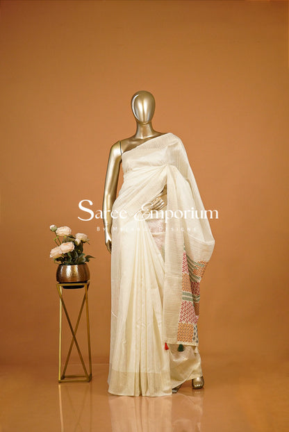 An off-white/cream saree draped .