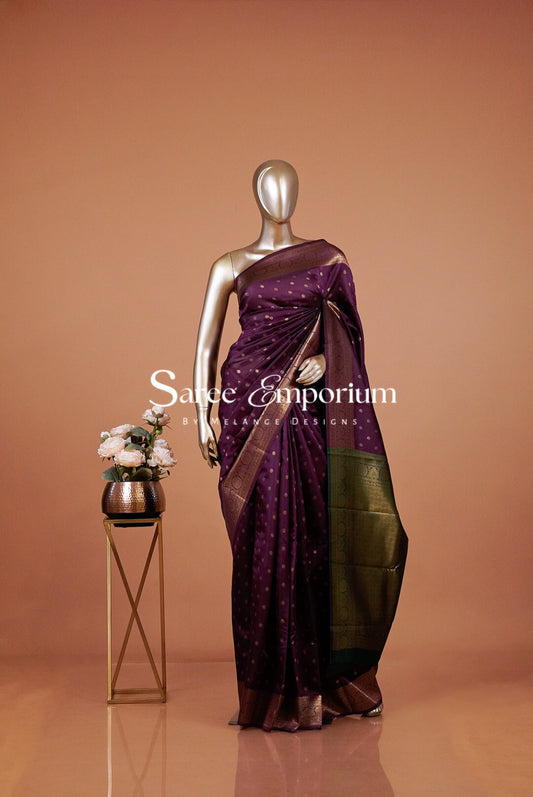 A metallic mannequin displays a purple sari with gold motifs and a dark green pallu.