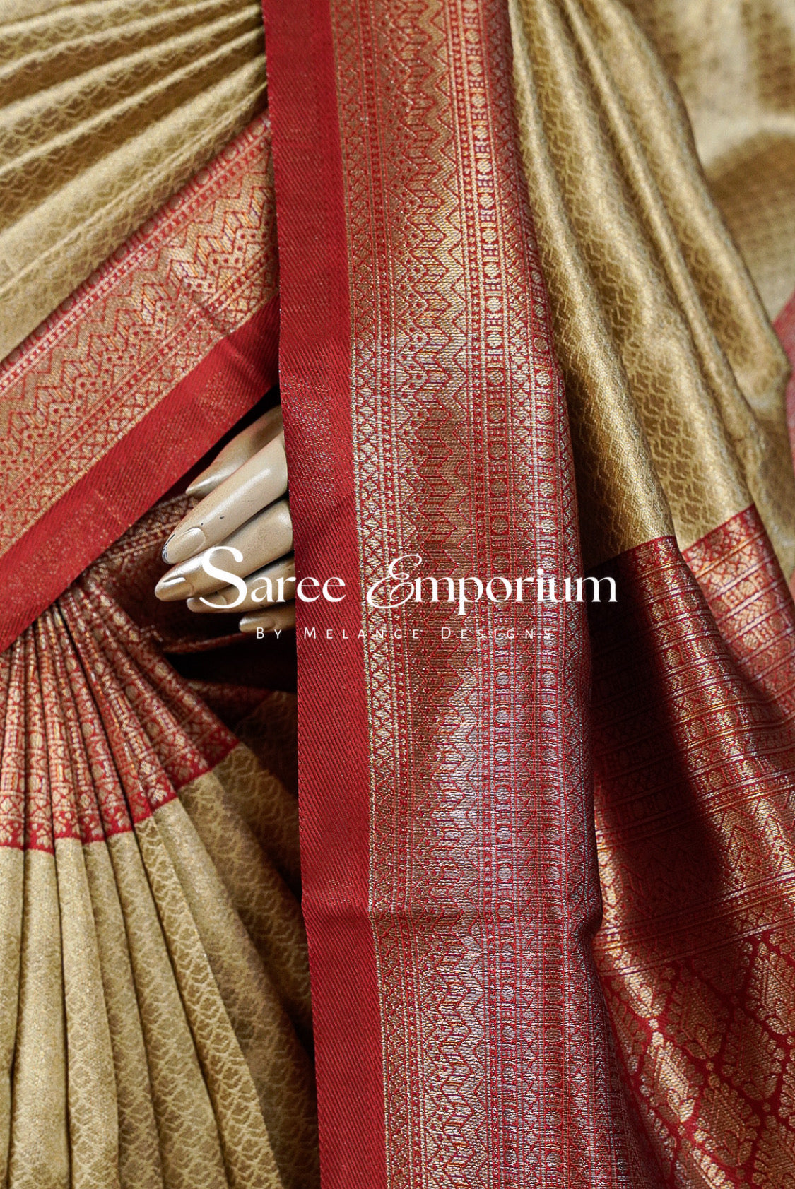 A close-up of a traditional Indian saree with a beige body, rich red borders, and intricate gold zari metallic embroidery.