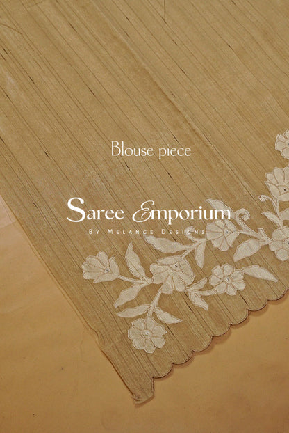 A close-up of a beige blouse piece with a scalloped edge and white floral embroidery.