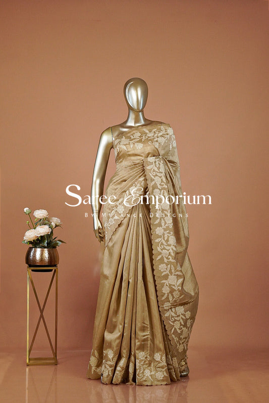 A metallic gold saree with intricate floral embroidery .