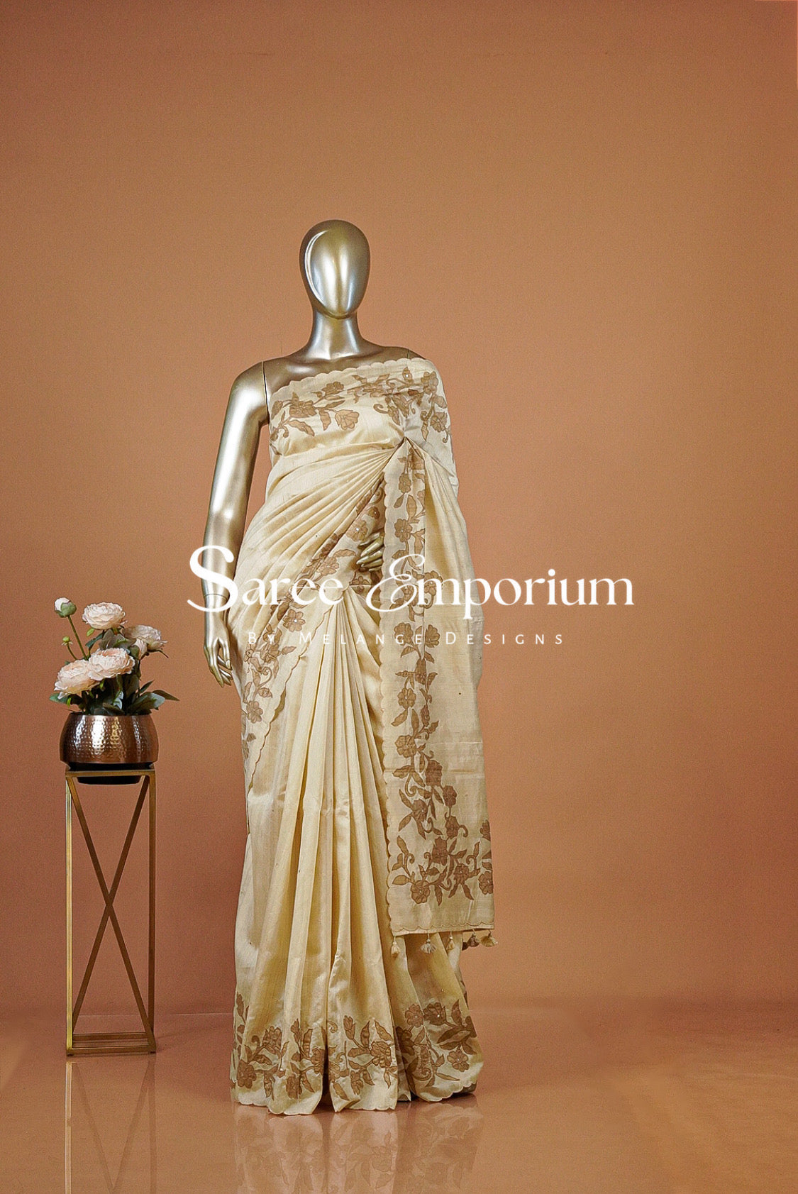 A cream-colored silk saree with gold floral embroidery .