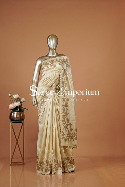 A cream-colored silk saree with gold floral embroidery .