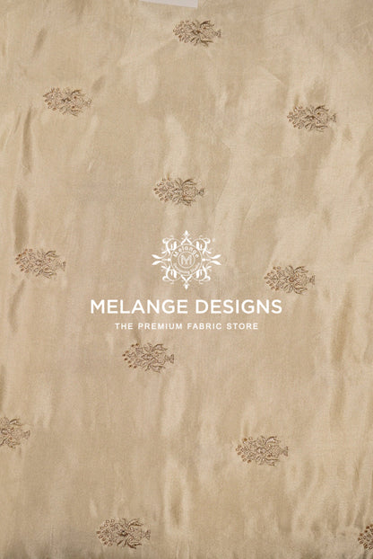 Beige Tissue Satin Embroidery Fabric Dyeable with a subtle sheen and scattered small metallic gold floral motifs.